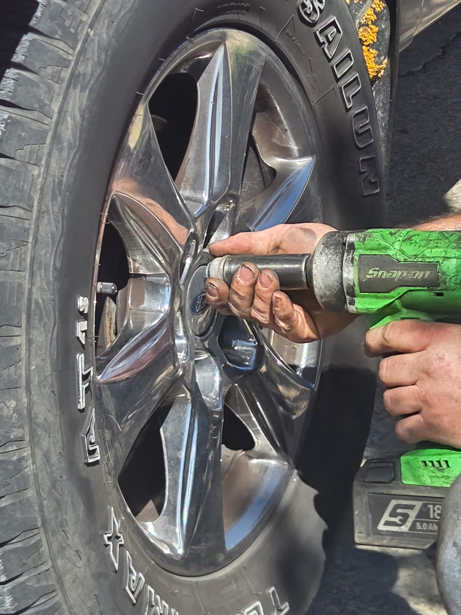 Mechanic using impact wrench on wheel